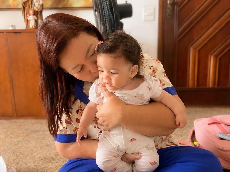 Dra. Sandra Barcellos com um bebê durante visita domiciliar